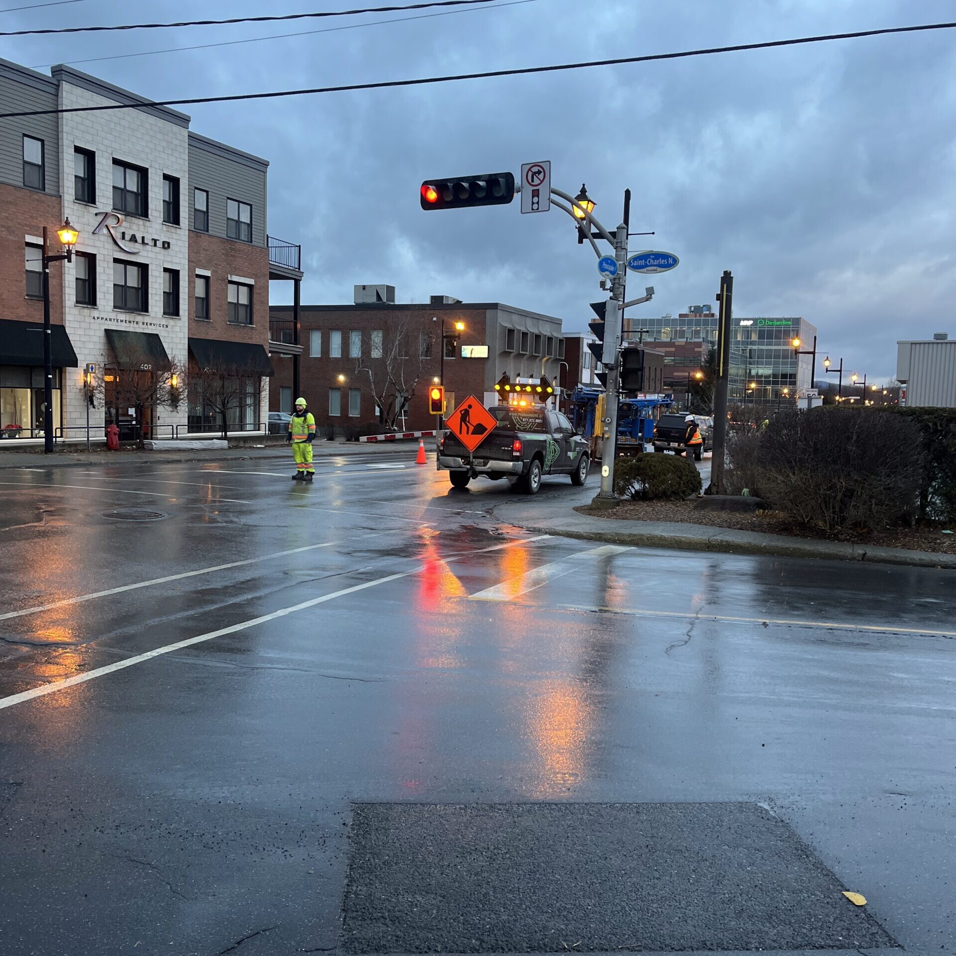 Coin de rue avec &eacute;quipe d&rsquo;asphaltage et signalisation en place.